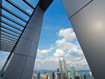 Low angle view of skyscrapers against cloudy sky