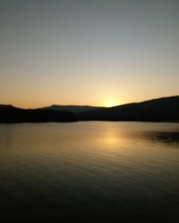 Scenic view of lake against clear sky during sunset