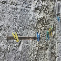 Close-up of clothespins on metal string against rough wall