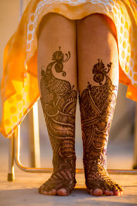 Low section of bride with henna tattoo on legs