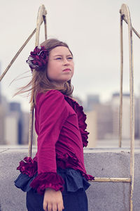 Side view of girl standing on building terrace against clear sky