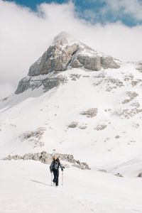 Anonymous athlete on skis on pico aunamendi in snowy pyrenees mountains under cloudy sky in navarre spain