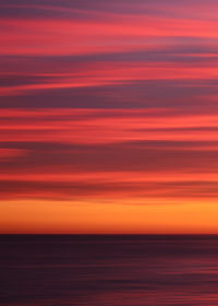 Scenic view of sea against dramatic sky at sunset