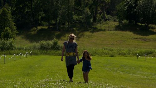 Mother and daughter walking on grassy field