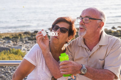 Couple blowing bubbles at beach during sunset