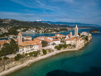 Buildings by sea against sky