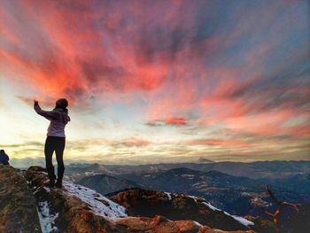 Rear view of man standing on mountain against sky