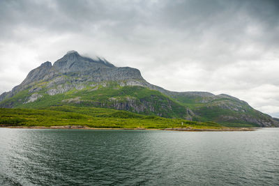 Scenic view of sea by mountains against sky