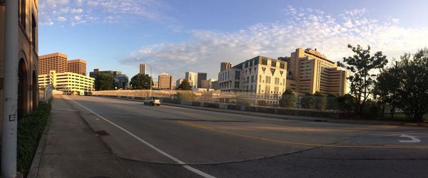 Road by buildings against sky in city