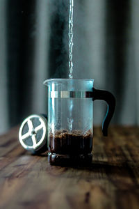 Close-up of water pouring in coffee maker on table