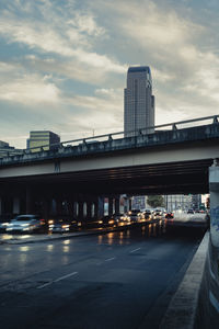 View of bridge in city against cloudy sky