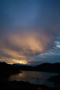 Scenic view of lake against dramatic sky during sunset