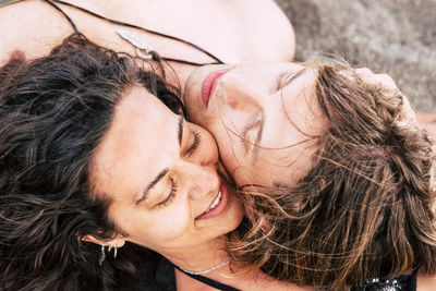 Close-up of smiling man and woman lying on sand at beach