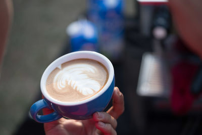 Close-up of hand holding coffee cup on table