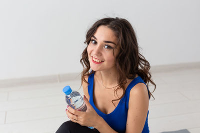 Portrait of smiling young woman holding ice cream against white background