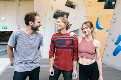 Portrait of smiling female standing with coach and male student in gym