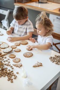 Siblings making cookies while sitting in kitchen