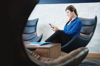 Woman using mobile phone while sitting on chair