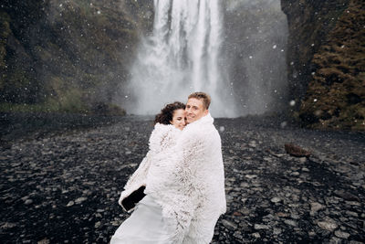 Rear view of couple standing against waterfall