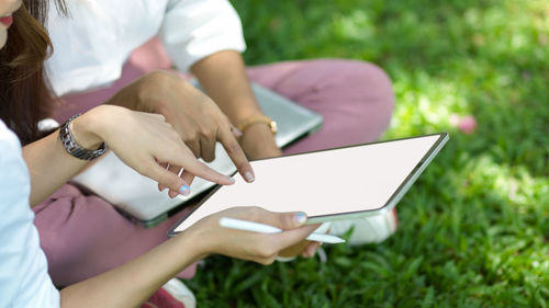 Midsection of women using digital tablet at park