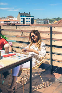 Woman sitting on table at outdoor cafe