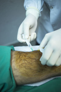 Cropped hand of surgeon inserting syringe in patient knee