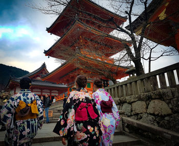 Rear view of people outside temple against building