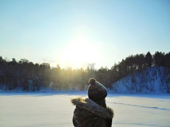 Rear view of person on snowy field against sky during winter