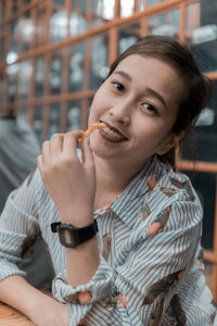 Portrait of smiling young woman having french fries