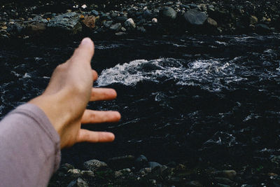 Cropped hand of person against river