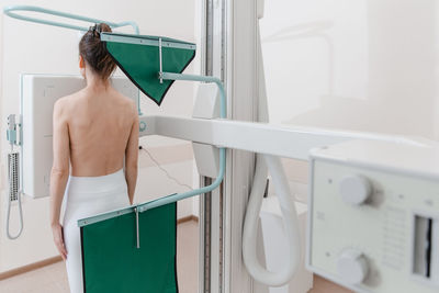 Rear view of woman holding suitcase in gym