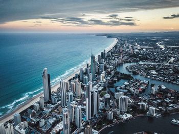 High angle view of modern buildings by sea against sky