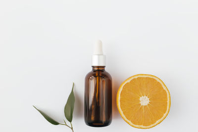 Orange essential oil in glass bottle with green leaf. cosmetic concept on white background, isolated