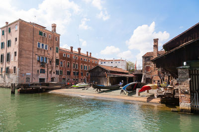 Canal amidst buildings in city against sky