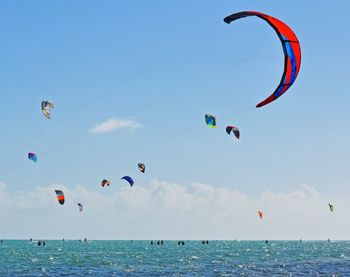 Parachutes flying over sea against sky