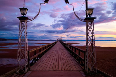 Pier on sea against cloudy sky