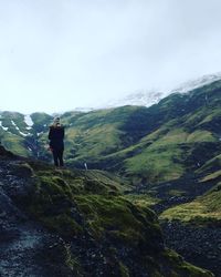 Rear view of woman standing on mountain against sky