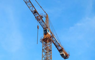 Low angle view of crane at construction site against sky