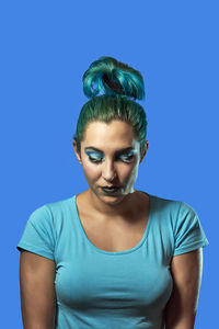 Portrait of young woman against blue background