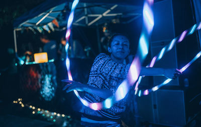 Woman performing with illuminated hoops at night at party