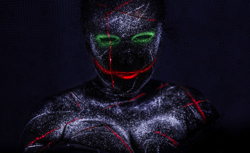 Portrait of person wearing mask against black background