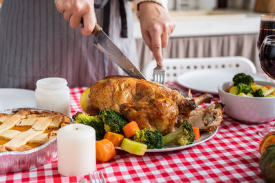 Woman celebrating holiday cooking traditional dinner at kitchen with turkey, vegetables and pumpkin