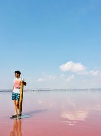 Boy standing on beach against sky