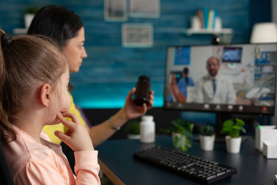 Woman using mobile phone while sitting on table