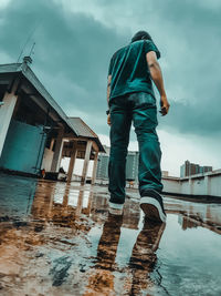 Full length of man standing in rain against sky