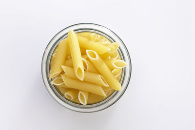 Close-up of pasta in jar over white background