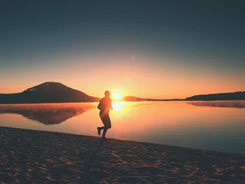 Woman on beach against sky during sunset