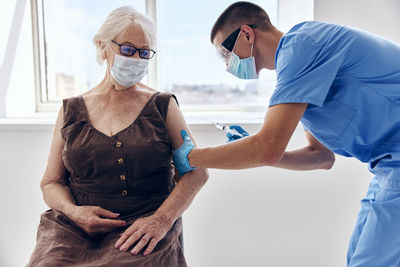 Doctor wearing mask vaccinating patient