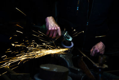 Midsection of craftsperson cutting metal with machine