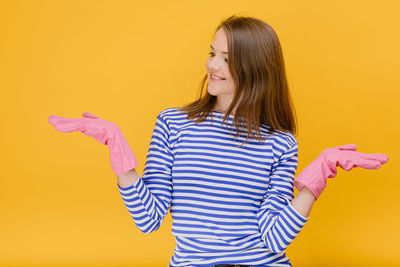 Young woman standing against yellow background